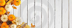 Autumn corner border of pumpkins, leaves and natural fall decor on a white wood banner background