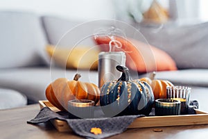 Autumn cozy composition for hygge home decor. Orange and gray pumpkins, just blown out candles with smoke on a tray with
