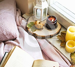 Autumn cozy window decorations lifestyle candle, book and blanke