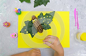 Autumn crafts. Child making fun butterfly from natural cone and leaves use paper and plasticine. Back to school. Ideas for