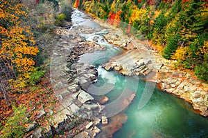 Autumn creek woods and rocks in forest mountain.