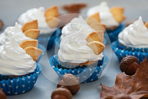 Autumn cupcakes decorated with cream and cookies leaves on gray wooden background. Soft focus. Thanksgiving day or Halloween