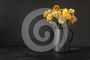 Autumn dark still life. Fall with yellow chrysanthemum flowers in clayware vase on black. photo