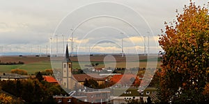 Autumn dawn or sunset above european roofs,trees,Catholic church,wind generators