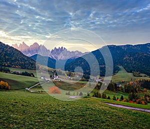 Autumn daybreak Santa Magdalena famous Italy Dolomites village view in front of the Geisler or Odle Dolomites mountain rocks.