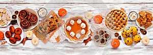 Autumn desserts table scene with a selection of traditional fall sweet treats over white wood banner