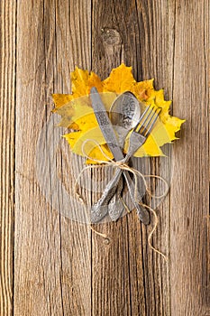 Autumn dinner place setting for Thanksgiving holiday with colorful maple leaves on rustic wooden boards