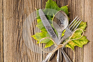 Autumn dinner place setting for Thanksgiving holiday with colorful maple leaves on rustic wooden boards