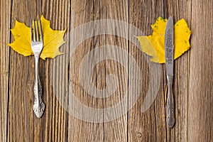 Autumn dinner place setting for Thanksgiving holiday with colorful maple leaves on rustic wooden boards