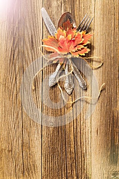 Autumn dinner place setting for Thanksgiving holiday with colorful maple leaves on rustic wooden boards