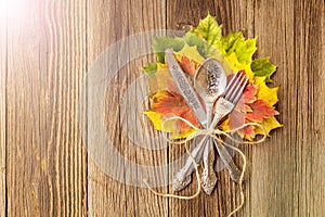 Autumn dinner place setting for Thanksgiving holiday with colorful maple leaves on rustic wooden boards