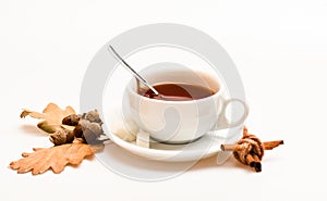 Autumn drink concept. Drink and acorn and oak leaves. Mug filled with black brewed tea, spoon and autumn fallen leaves