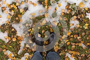 Autumn fall concept with yellow leaves, rain boots and first snow