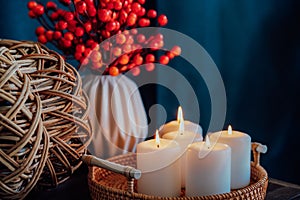 Autumn fall cozy mood composition for hygge home decor. Part of wicker pumpkin, burning candles on a tray and seasonal