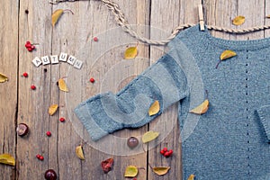 Autumn fall flat lay, top view. Warm knitted sweater, Fall Leaves, chestnuts, rowan berry and pumpkin with inscription `autumn`