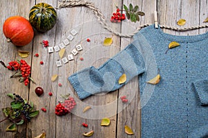 Autumn fall flat lay, top view. Warm knitted sweater, Fall Leaves, chestnuts, rowan berry and pumpkin with inscription `autumn he