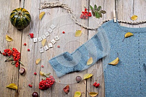 Autumn fall flat lay, top view. Warm knitted sweater, Fall Leaves, chestnuts, rowan berry and pumpkin with inscription `autumn h