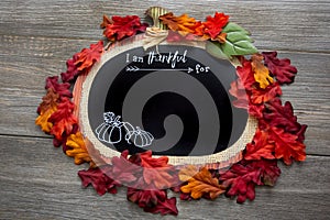 A autumn, fall inspired I am thankful for background surrounded by fall leaves on a wooden table. Perfect for a Thanksgiving messa