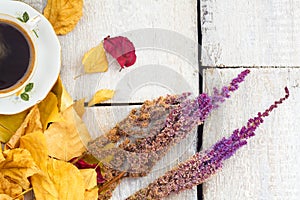 Autumn, fall leaves, hot steaming cup of coffee and flowers on wooden table background. Seasonal, morning coffee, sunday relax and