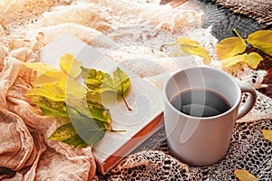 Autumn, fall leaves, hot steaming cup of coffee and a warm scarf on wooden table background. Seasonal, morning coffee