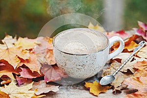 Autumn, fall leaves, hot steaming cup of coffee on wooden table background. Seasonal, morning coffee, Sunday relaxing and still li