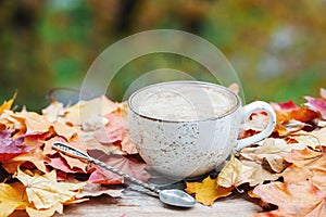 Autumn, fall leaves, hot steaming cup of coffee on wooden table background. Seasonal, morning coffee, Sunday relaxing and still li