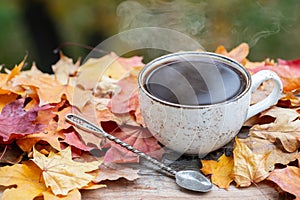 Autumn, fall leaves, hot steaming cup of coffee on wooden table background. Seasonal, morning coffee, Sunday relaxing and still li