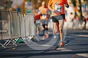 Autumn fall marathon race in city. Marathon running race, people feet on autumn road. Runners run urban marathon in the downtown