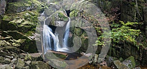 Autumn fall mountain waterfall stream in the rocks with colorful fallen dry leaves, landscape, natural seasonal background