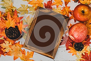 Autumn and Fall season. Empty photo frame and fake maple leaf on wood table. Harvest cornucopia and Thanksgiving day