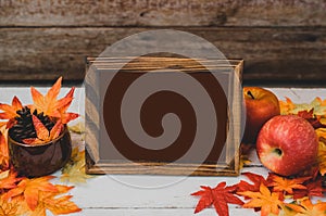 Autumn and Fall season. Empty photo frame and fake maple leaf on wood table. Harvest cornucopia and Thanksgiving day