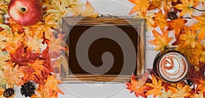 Autumn and Fall season. Hot chocolate with photo frame and fake maple leaf on wood table. Harvest cornucopia and Thanksgiving