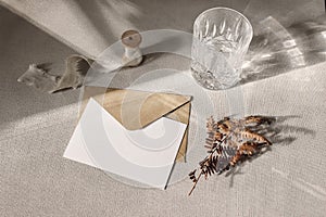 Autumn, fall stationery mockup scene. Blank greeting card, invitation, craft paper envelope, dry fern leaf and sparkling