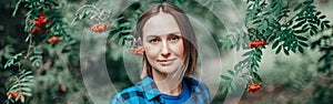 Autumn fall summer woman portrait in rowan tree berries. Closeup of pensive Caucasian middle age woman in park outdoor looking at