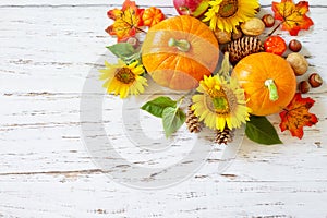 Autumn, fall, Thanksgiving concept. Pumpkins, sunflowers, apples and fallen leaves on rustic wooden table.