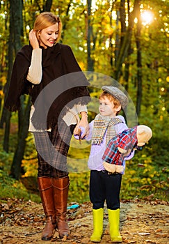 Autumn Family. Happy Mother and little son walking together in autumnal park.