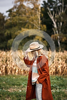 Autumn fashion collection. Stylish woman wearing red coat, sweater and hat in nature