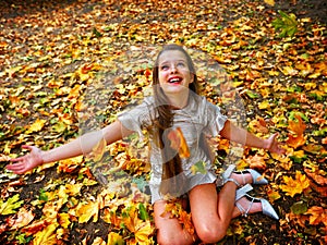 Autumn fashion dress child girl sitting fall leaves park outdoor.