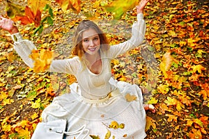 Autumn fashion dress woman sitting fall leaves city park outdoor.