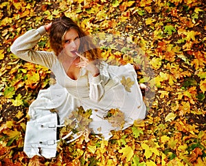 Autumn fashion dress woman sitting fall leaves city park outdoor.