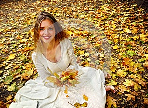 Autumn fashion dress woman sitting fall leaves city park outdoor.