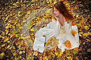 Autumn fashion dress woman sitting fall leaves city park outdoor.