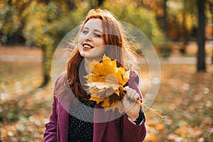 Autumn fashion, earth tones style, bright fall color palette. Portrait of red-haired girl in purple coat