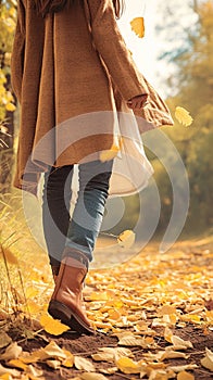 Autumn fashion woman in jeans and boots walking in park