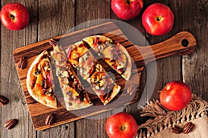 Autumn flat bread with apples, pecans, red onion, and blue cheese, top view table scene on wood