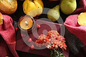 Autumn flat lay composition with beautiful orange chrysanthemum flowers, scented candle and rosehip berries on wooden table