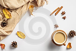 Autumn flat lay composition. Flat lay, top view coffee cup, pine cones, cinnamon sticks, beige scarf, dry leaves on white table.