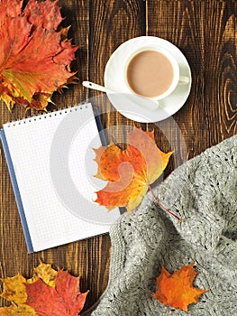Autumn. flat lay. Sheets, a warm scarf, a Cup of tea and notebook with pen on wooden rustic background