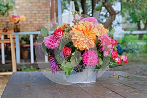 Autumn flowers: roses, asters, dahilia in the garden on a wooden table. Bright rural design. Sunny day