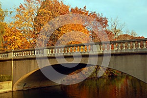 Autumn foliage surrounds a stone bridge spanning a lake